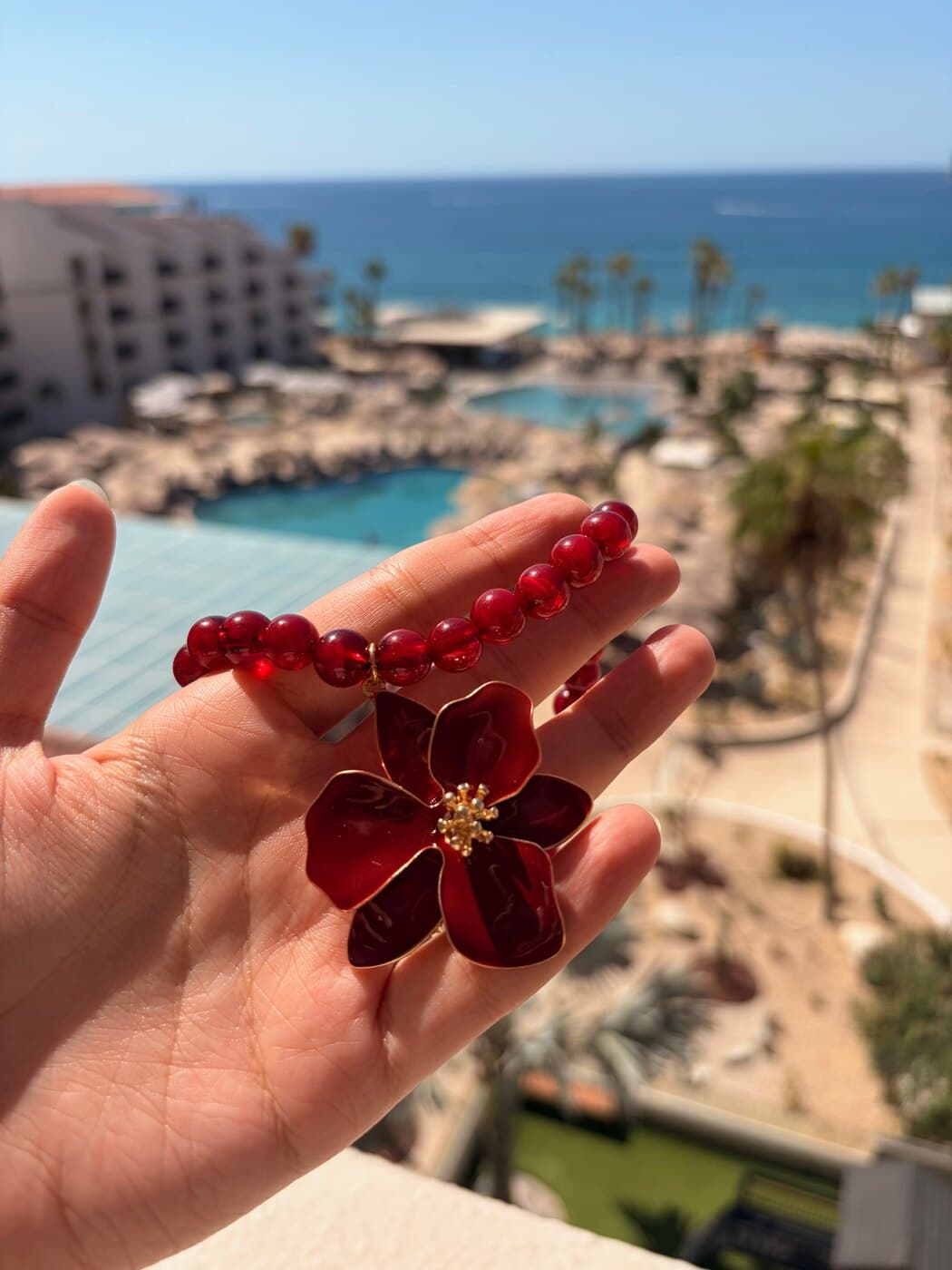 Collar Amour sostenido en la mano frente a una piscina